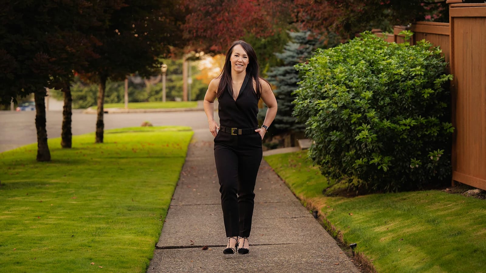 Lynea Carver walking forward on a tree-lined path — momentum, action, the kind of person this training is built for